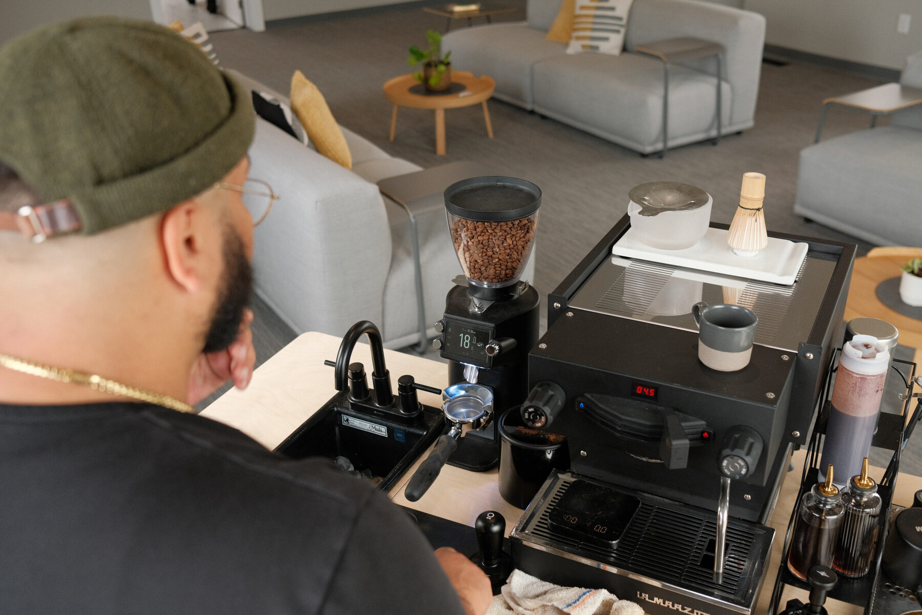 Looking over the bar at the grinder, machine and matcha set, lounge seating beyond