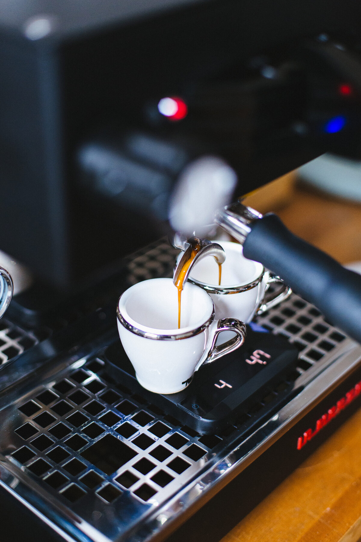 A double shot of espresso pulling into two cups on a professional machine